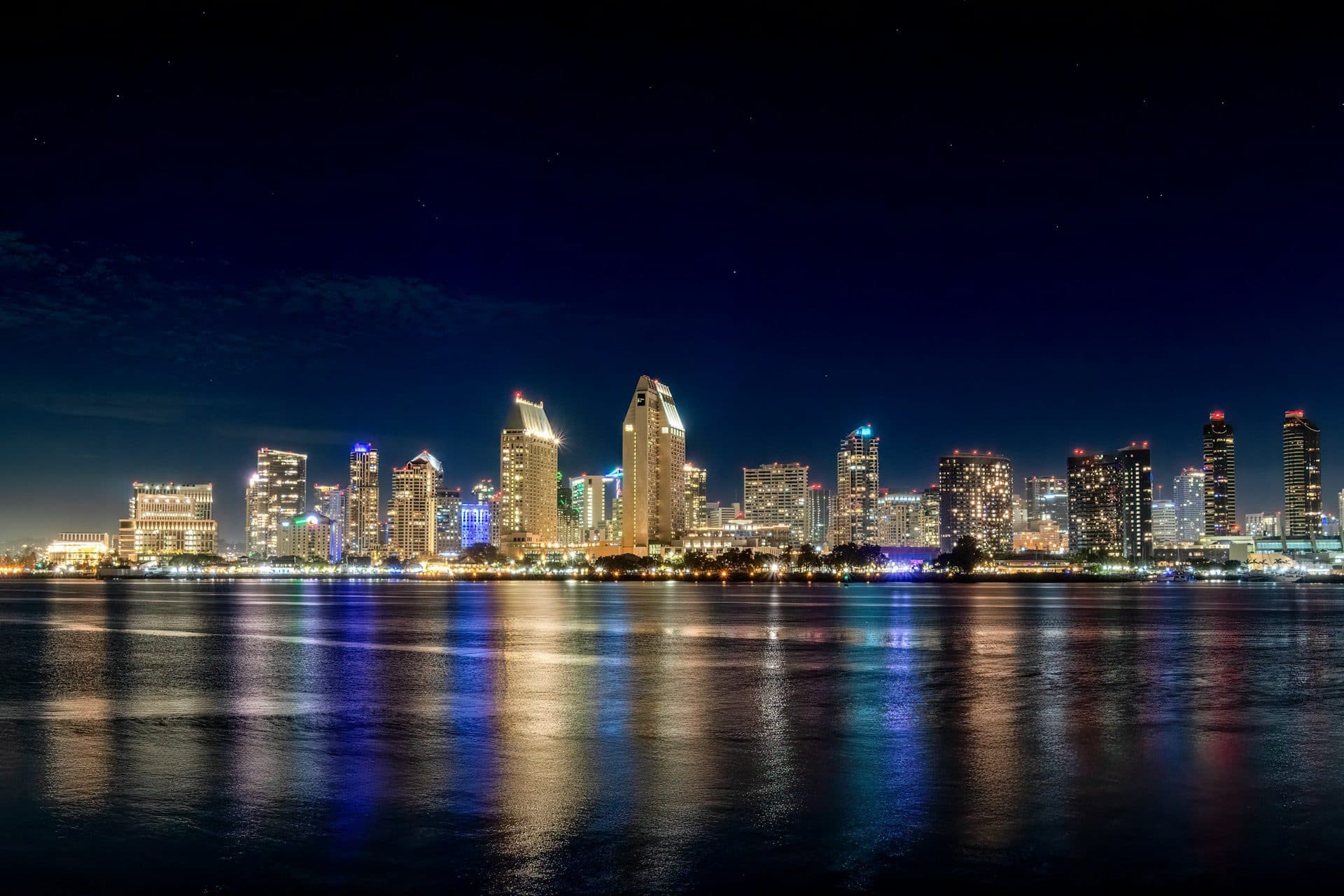 Downtown San Diego skyline at night, lit up and reflected in San Diego Bay